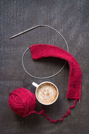 Knitting with red yarn, needles and a cup of coffeeの写真素材