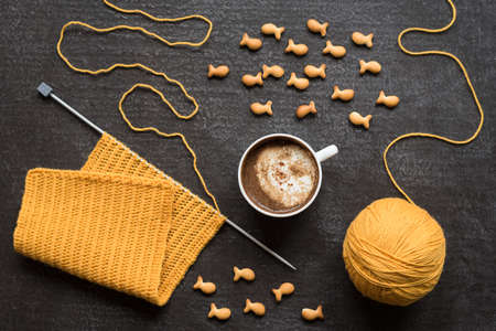 Knitting, cup of coffee and fish crackers on grunge background.の写真素材