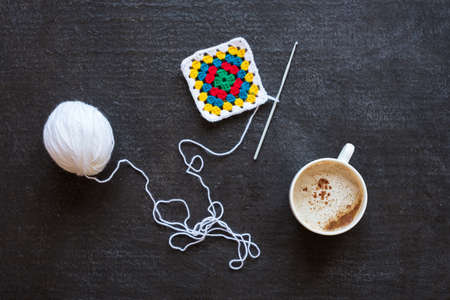 White yarn, crocheted multi-colored motif and coffeeの写真素材