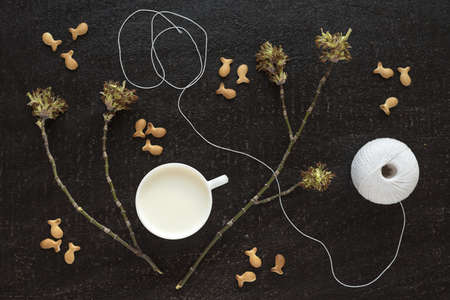 Composition with blossoming twigs, milk, a cotton skein and cookies on black backgroundの写真素材