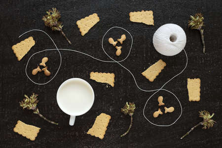 Composition with blossoming twigs, milk, a cotton skein and cookies on black backgroundの写真素材