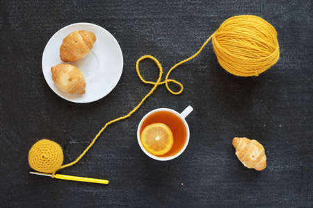 Lemon tea, yellow crocheting and croissants on black backgroundの写真素材