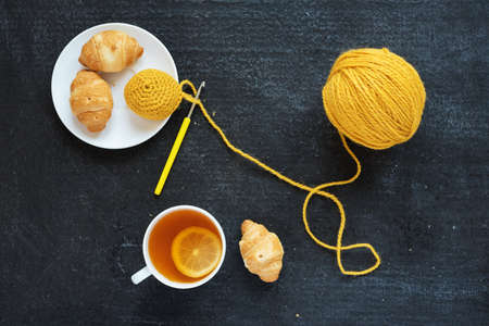 Lemon tea, yellow crocheting and croissants on black backgroundの写真素材