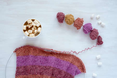 Cup of coffee with marsh mallow and knitting on white backgroundの写真素材
