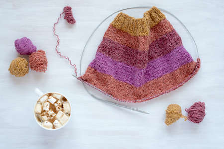 Cup of coffee with marsh mallow and knitting on white backgroundの写真素材