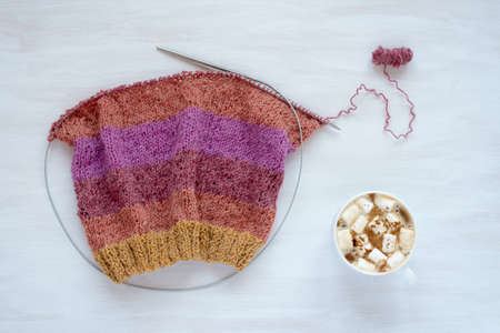Cup of coffee with marsh mallow and knitting on white backgroundの写真素材