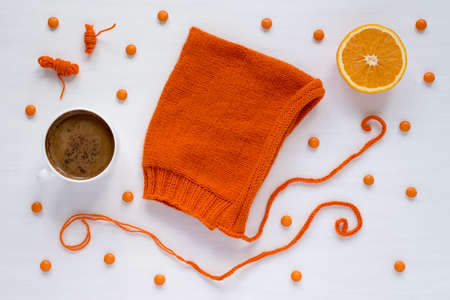 Cup of coffee, orange, candies and a handmade hat on white backgroundの写真素材