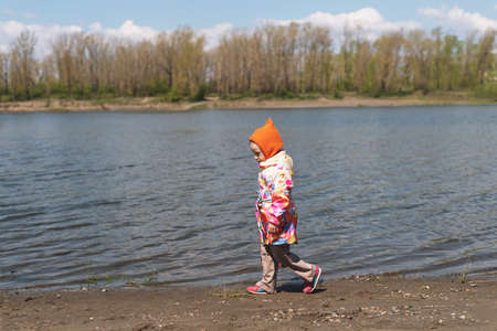 little girl walking along the riverbank on a sunny day.の写真素材