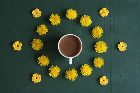 Cup of coffee, dandelions and crocheted flowers on green background.の写真素材