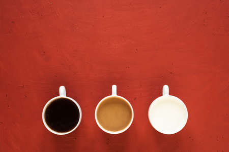 Three cups with milk and coffee on a red background.