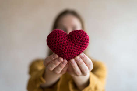 Woman with a crocheted heart. Soft focus on a heart. Woman is unfocused.の写真素材