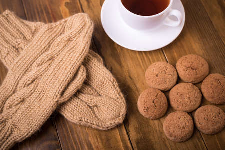 Coffee, mittens and oat cookie on woodの写真素材