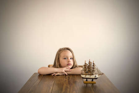 Dreamy girl at a table with a little boat