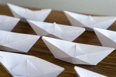 Origami paper boats on a wooden tableの写真素材