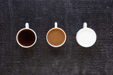 Three cups with black coffee, coffee with milk and just milk on black background.の写真素材