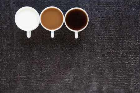 Three cups with black coffee, coffee with milk and just milk on black background.の写真素材