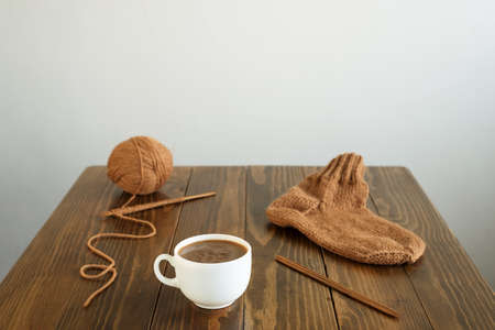 Cup of coffee, a woolen sock and knitting with bamboo needles on a wooden table.の写真素材