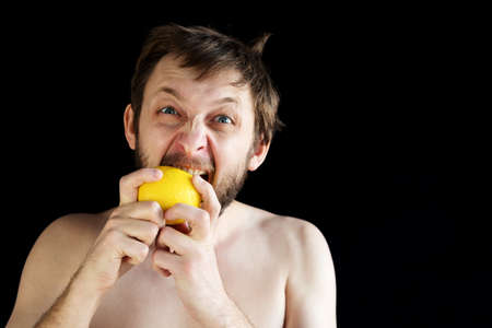 Dishevelled man eating a lemon