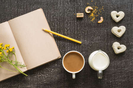 Diary with coffee, flowers and cookies on blackの写真素材