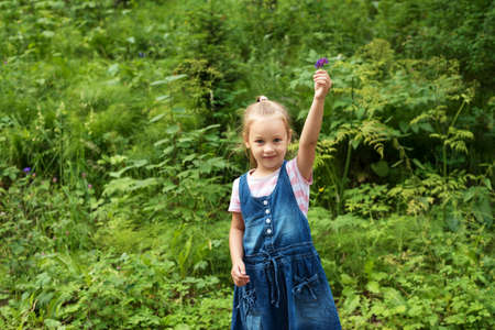 Little girl with a wildflower in the forestの写真素材