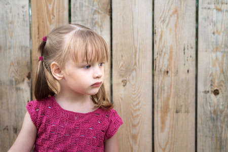 Little girl on a wooden fence backgroundの写真素材