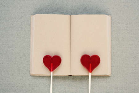 Two heart-shaped lollipops on an old diaryの写真素材