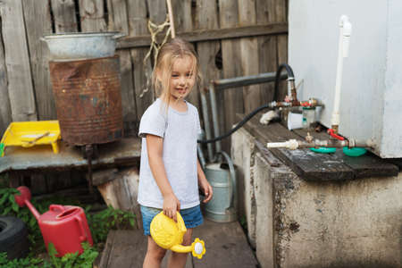 Little dirty-faced girl with a watering-canの写真素材