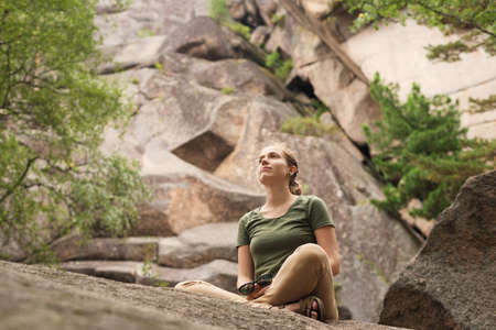 Young woman sitting on the rock in wild reserveの写真素材
