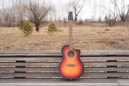 Acoustic guitar on a bench outdoors in the parkの写真素材