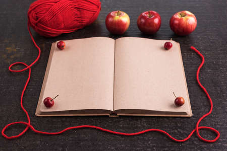 Autumn composition with leaves, apples, red yarn and an old empty book.の写真素材