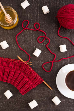 Composition with coffee, honey, red knitting and marsh-mallows on black grunge background.の写真素材