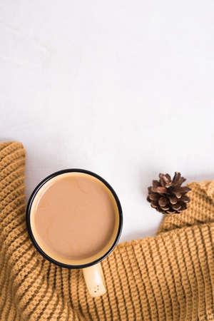 Knitted shawl, cup of coffee and cones on white background