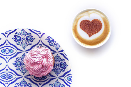 cappuccino heart in a white cup with a cupcake and creamの写真素材