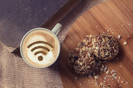 A cup of cappuccino coffee with painted cinnamon on milk foam with a wi-fi symbolの写真素材