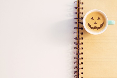 a cup of cappuccino coffee with a picture of a halloween symbol from cinnamon on milk foamの写真素材