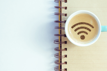 A cup of cappuccino coffee with painted cinnamon on milk foam with a wi-fi symbolの写真素材
