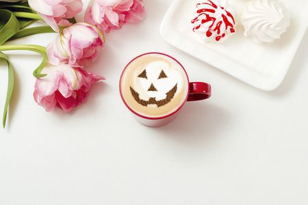 a cup of cappuccino coffee with a picture of a halloween symbol from cinnamon on milk foamの写真素材