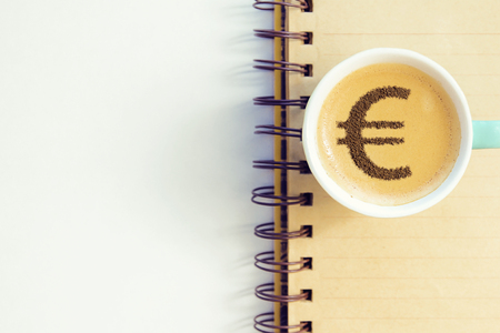 cup of coffee cappuccino with a picture of a Euro sign from cinnamon on milk foamの写真素材