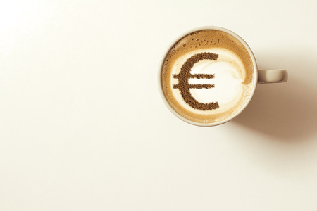 cup of coffee cappuccino with a picture of a Euro sign from cinnamon on milk foamの写真素材
