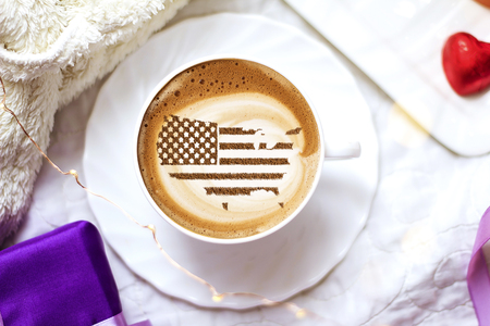 Flag of the United States of America in the form of territorial borders on a cappuccino coffee cup close-upの写真素材