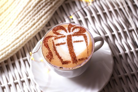 Christmas coffee in a white cup with a gift picture on white foamの写真素材