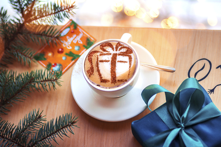 Christmas coffee in a white cup with a gift picture on white foamの写真素材