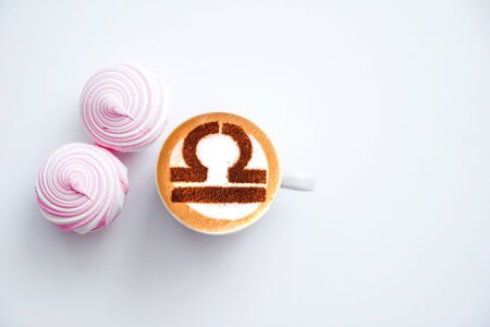 white cup of coffee with the symbol of the zodiac Libra on milk foam