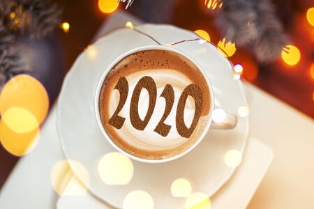 Figures 2020 as a symbol of the New Year on cups of hot aromatic coffee on a bright red background among stars and marshmallows. Top view, flat layの写真素材