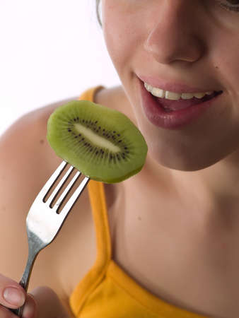 Beautiful teen girl eats kiwi with forkの写真素材