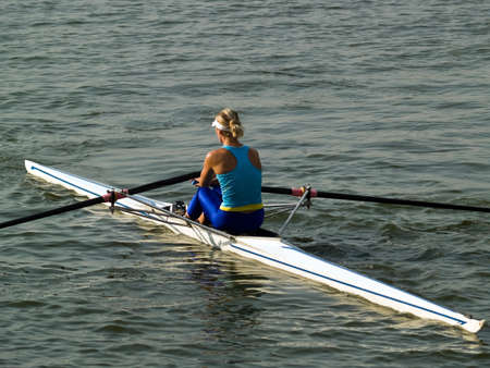 Sporty young lady rowing in boat on waterの写真素材