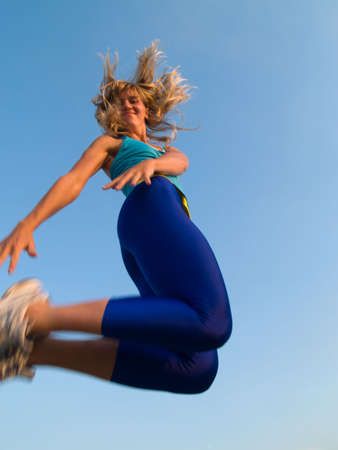 Beautiful fit blond girl jumping smiling cheerfulの写真素材