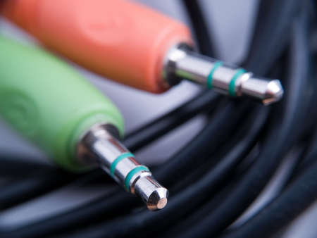 Two multicolored audio jacks with cables on grayの写真素材
