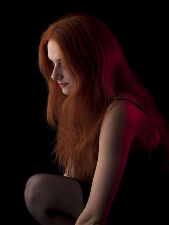 Beautiful red-haired young lady in evening dress on black backgroundの写真素材