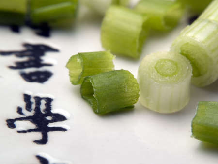 Cut green onion on asian plate with hieroglyphsの写真素材